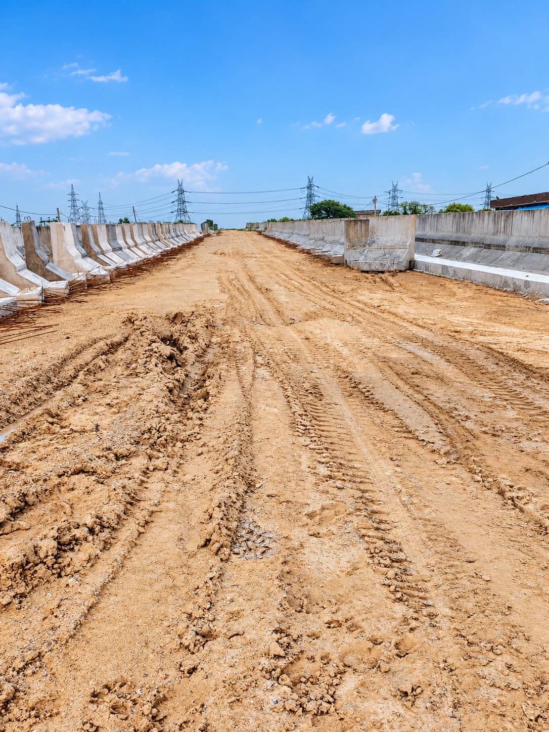 Approach embankment between precast RE wall panels and crash barrier units, transmission towers behind
