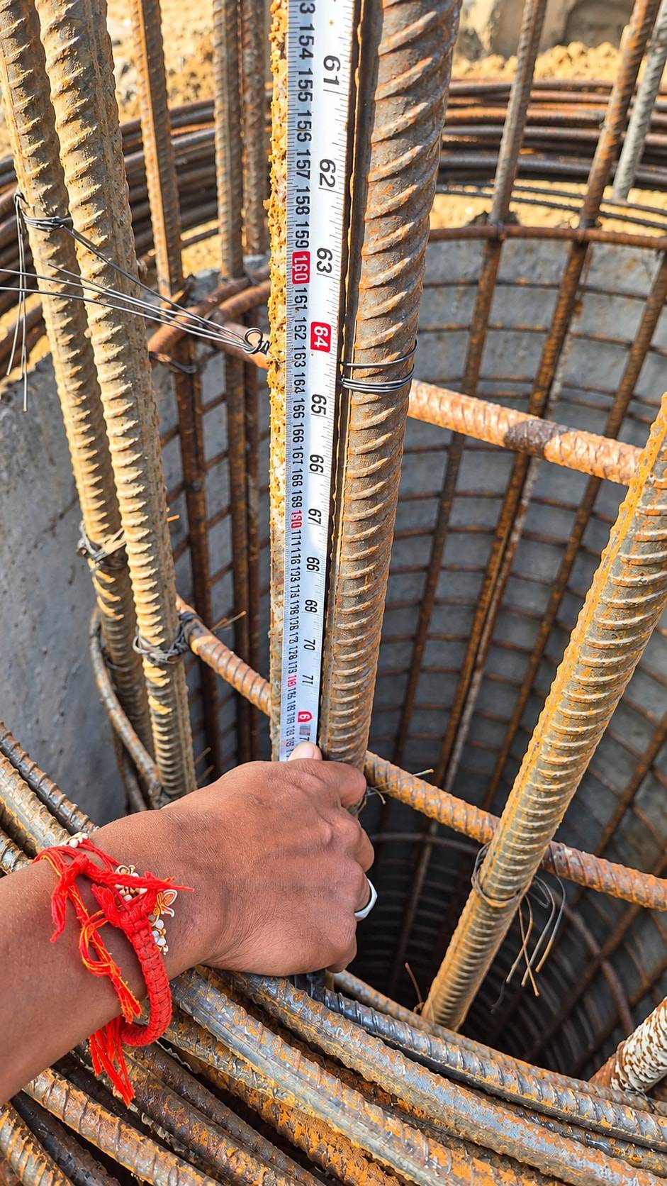 A tape measure held against vertical bars of a pile reinforcement cage
