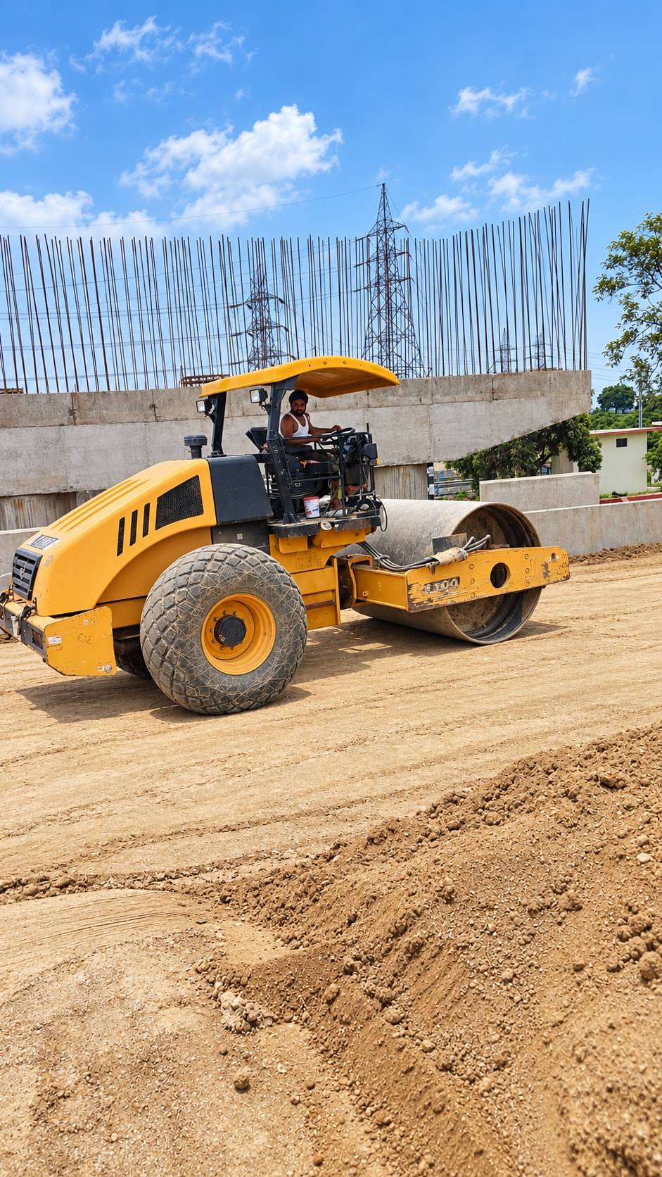 Single drum soil compactor rolling formation in front of a concrete abutment