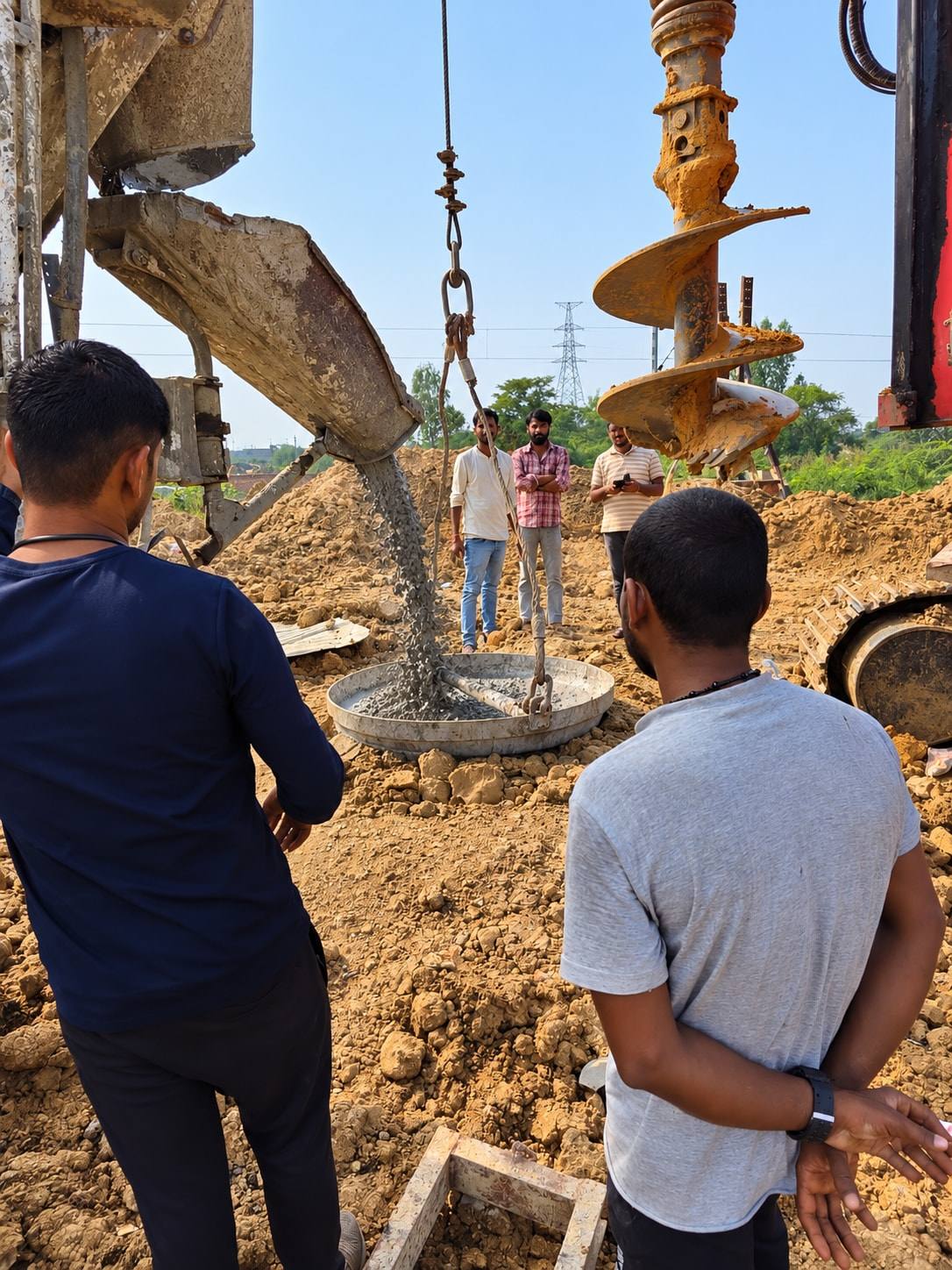 Concrete pouring from a chute into a tremie hopper while engineers watch